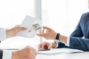 cropped view of man giving envelope with money to business partner
